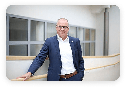 Mann in Business-Outfit vor einer Indoor-Fensterfront