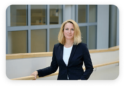 Frau in Business-Outfit vor einer Indoor-Fensterfront