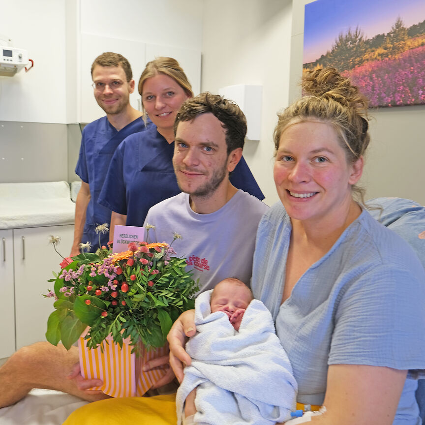 Zwei Personen vom medizinischen Fachpersonal und Eltern mit ihrem Baby.