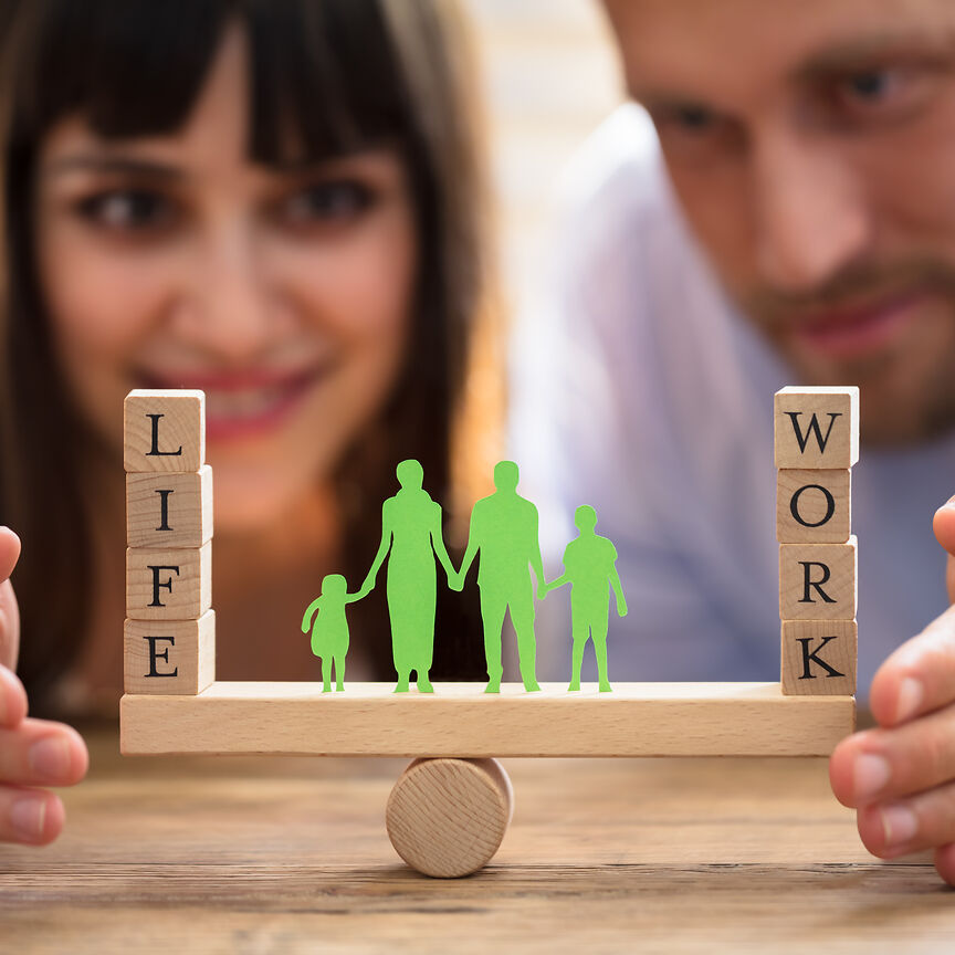 Frau und Mann balancieren in Holzbauklätzen die Wörter "life" und "work"