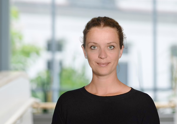 Lena Stange Lächelnde Frau vor verschwommenen Hintergrund in schwarzem Pullover